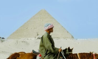 A man rides a horse against the iconic backdrop of the Giza Pyramid, Egypt.